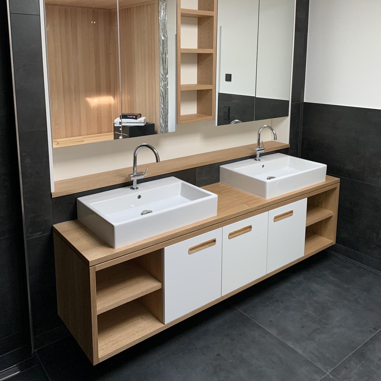 Maßgefertigte Badmöbel mit Doppelwaschbecken Eine maßgefertigte Badmöbel-Lösung mit zwei Waschbecken, Holzunterschrank und integrierten Regalfächern. Über den Waschbecken befinden sich große Spiegel. Badmöbel nach Maß.