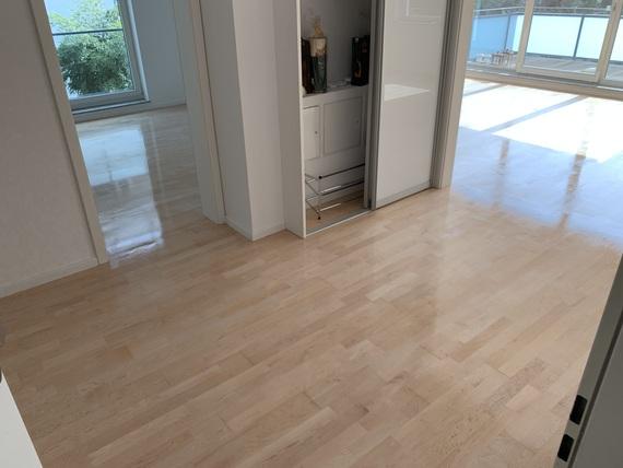 Individuell verlegter Holzboden in einem modernen Apartment Ein heller, individuell verlegter Holzboden verbindet mehrere Räume eines Apartments. Das Bild zeigt reflektierendes Licht auf dem Boden und einen Ausblick auf den Balkon. Individueller Boden.