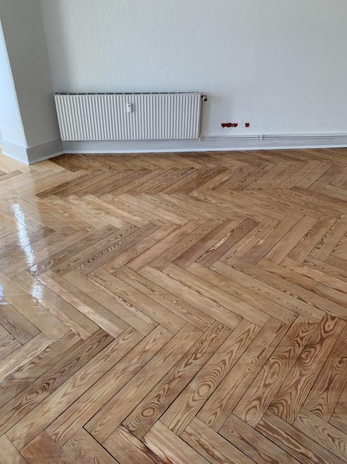 Fischgrät-Parkettboden in einem leeren Raum Bild zeigt einen detailreichen Fischgrät-Parkettboden mit glänzender Oberfläche in einem leeren Raum