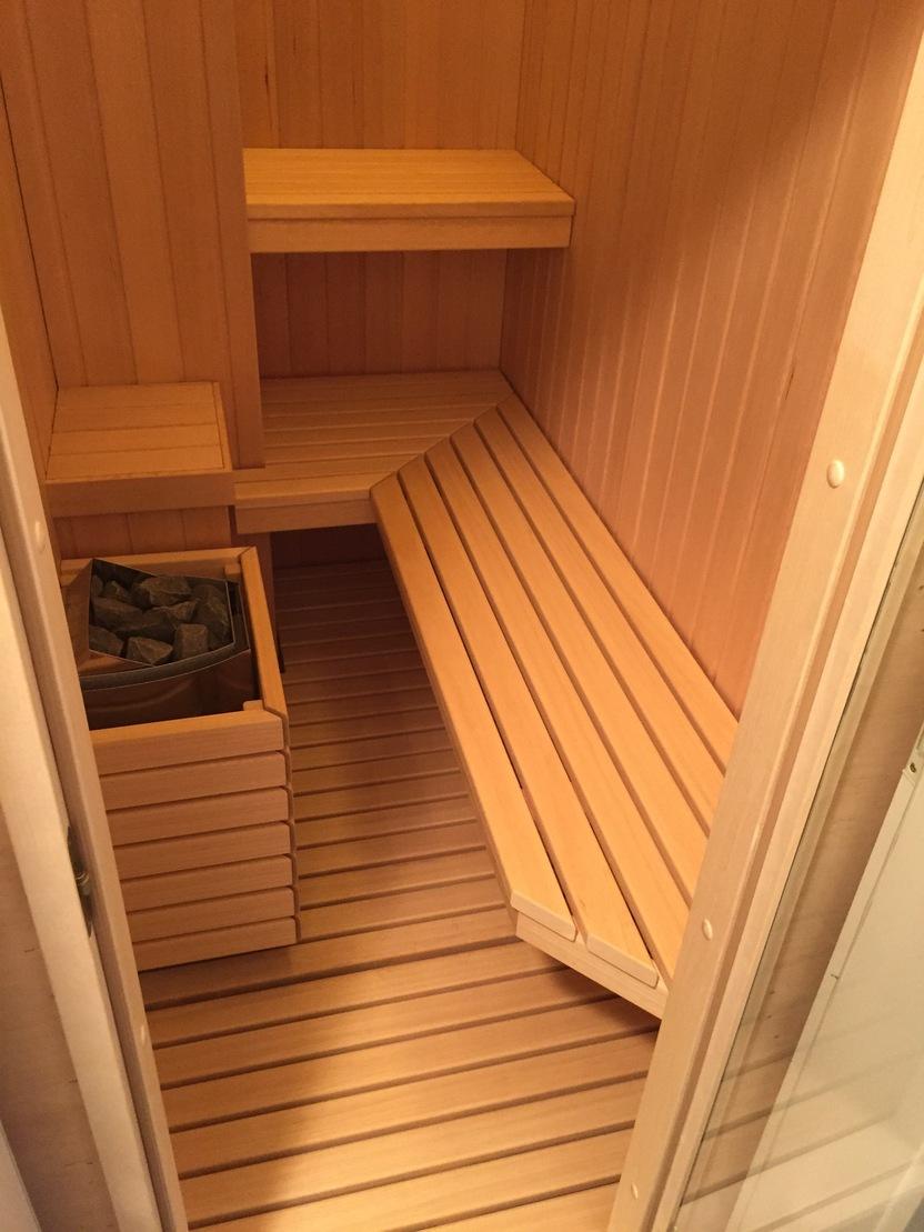 Innenansicht einer Holzsauna Bild zeigt das Innere einer Sauna mit honigfarbenen Holzbänken und vertikalen Holzpaneelen an den Wänden.