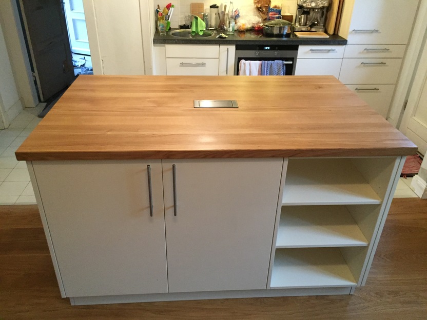 Eine Kücheninsel mit einer robusten Holzarbeitsplatte und einem integrierten Edelstahlgrill in der Mitte.