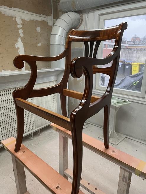 Restaurierung eines antiken Holzstuhls Ein antiker Holzstuhl befindet sich in der Restaurierung. Der Stuhl glänzt nach der Politur und ist für weitere Arbeiten vorbereitet. Der Raum zeigt eine Werkstattumgebung. Restaurierung.