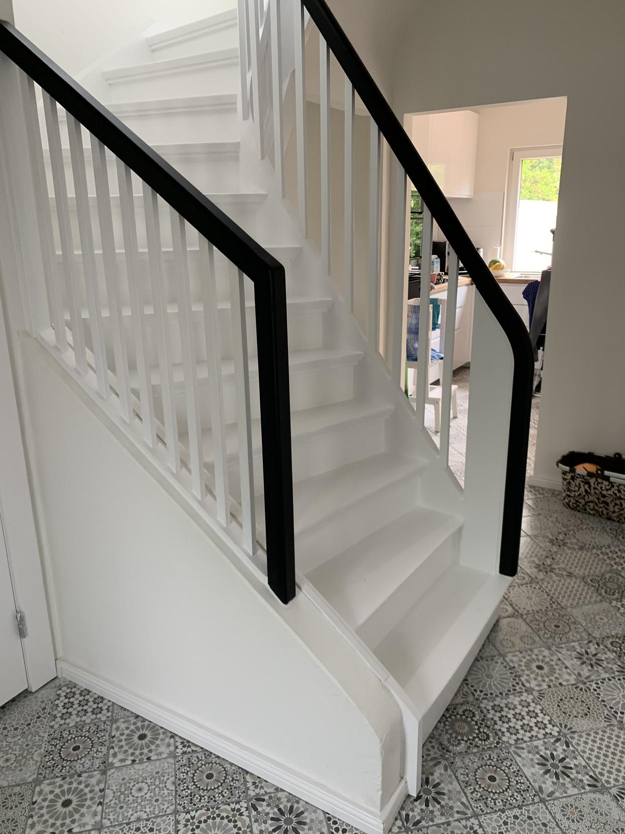 Bild einer eleganten, weißen Wendeltreppe mit geschlossenen Stufen auf einem dekorativen, gemusterten Fliesenboden