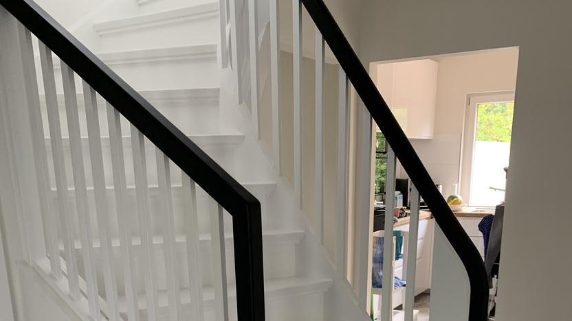 Weiße Wendeltreppe mit schwarzem Handlauf Bild einer eleganten, weißen Wendeltreppe mit geschlossenen Stufen auf einem dekorativen, gemusterten Fliesenboden