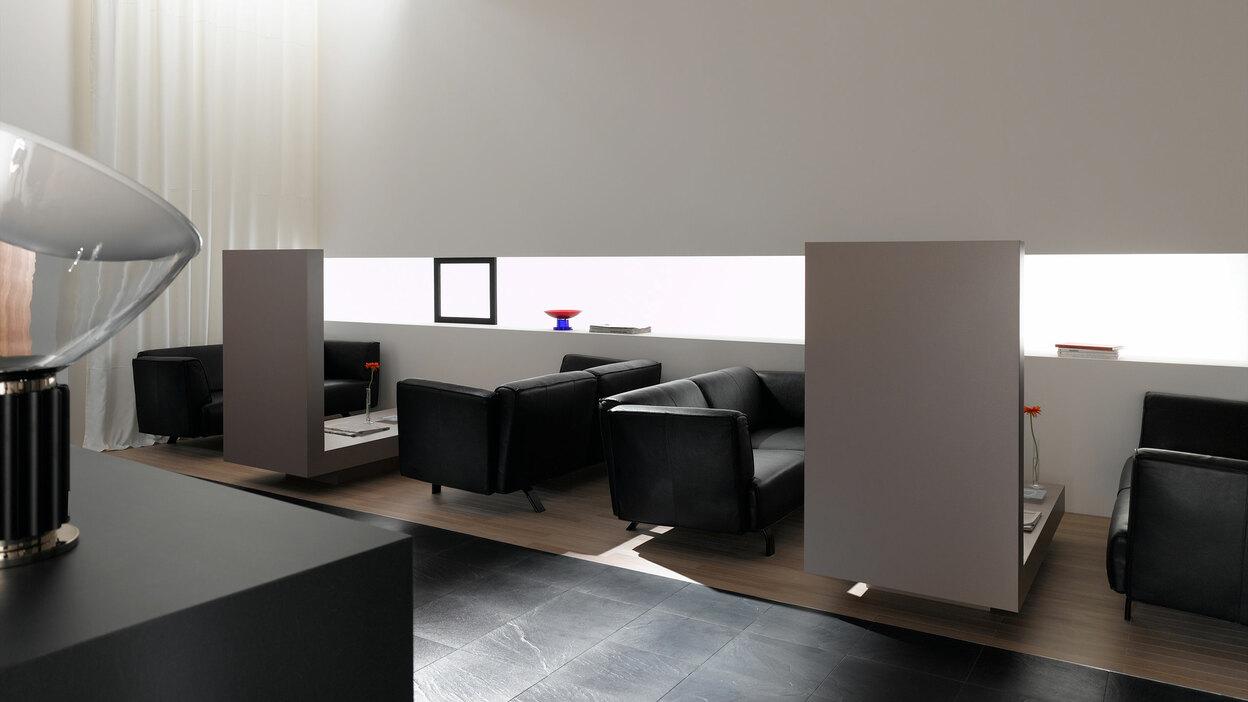 Hotellobby mit Trennwänden aus Holz und schwarzen Ledersofas