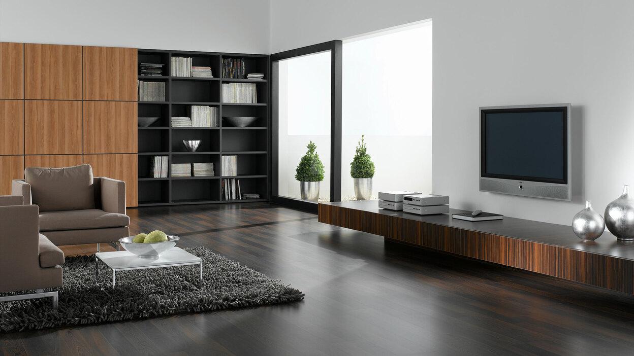 Wohnraumimpression mit verschieden dunklen Holzoberflächen für Einbauschrank, Sideboard und Bodenbelag