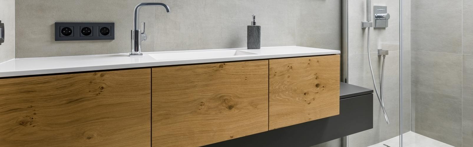 Asymmetrischer Waschtisch mit Schubläden in Echtholz und schwarzer Lackierung auf weiterem schmalen Unterschrank.